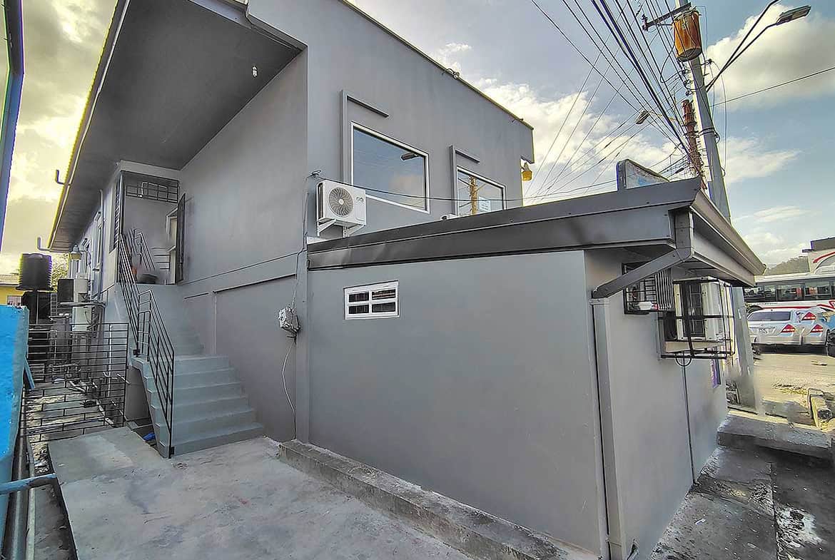 Cornerstone- Modern commercial building in Curepe with gray exterior and stairs.