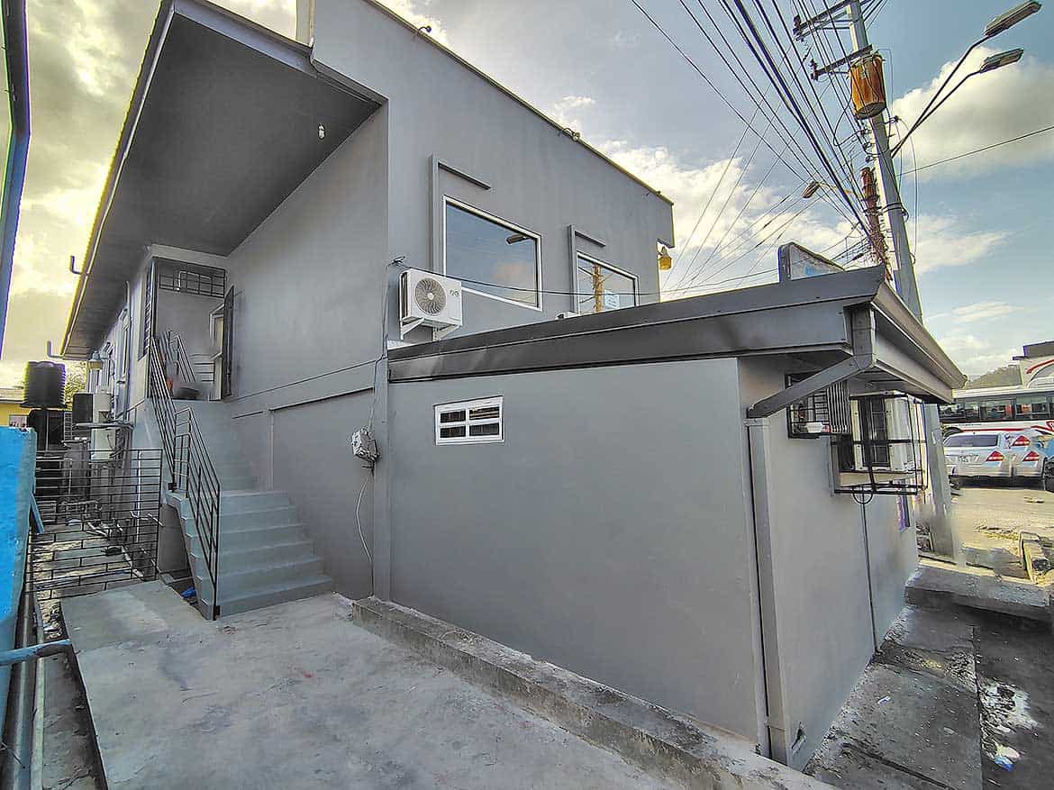 Cornerstone- Modern commercial building in Curepe with gray exterior and stairs.