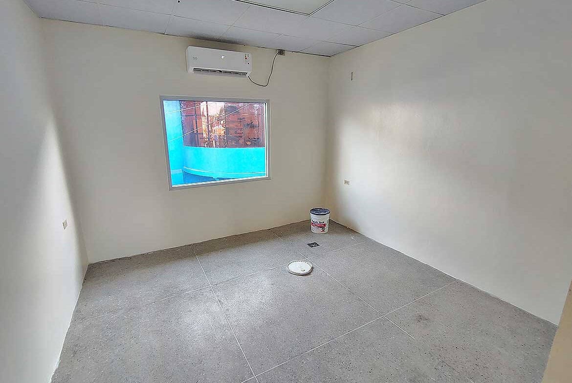 Cornerstone- Empty commercial room with window and air conditioning unit in Curepe.