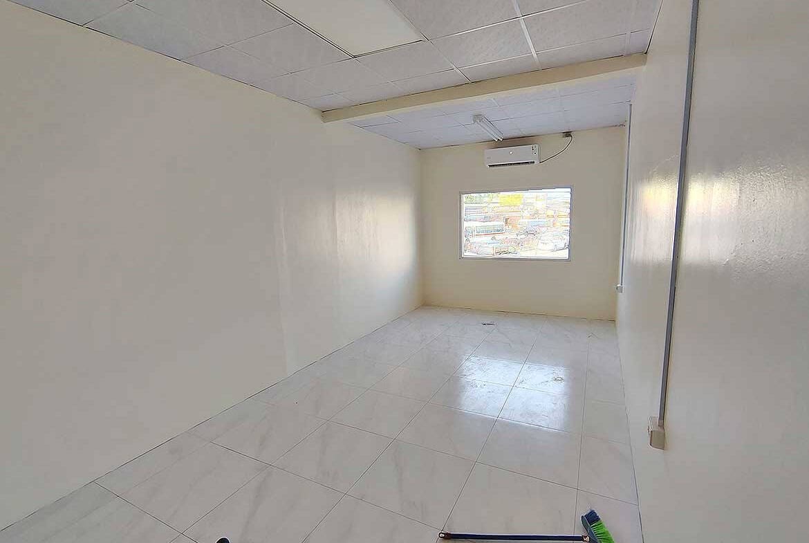 Cornerstone- Empty commercial room with white walls and window in Curepe.