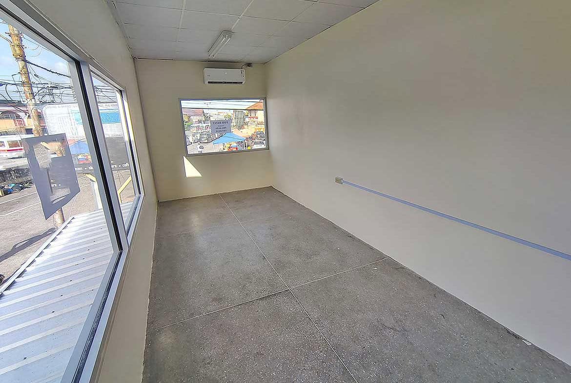 Cornerstone- Empty commercial space with large windows in Curepe for lease or sale.