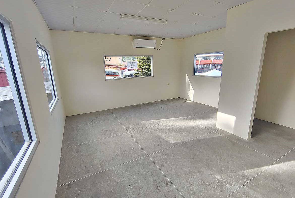 Cornerstone- Empty commercial space with large windows in Curepe for lease or sale.