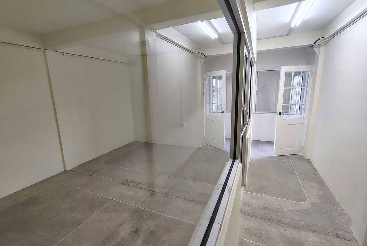 Cornerstone- Empty commercial space with glass partition and white walls in Curepe.