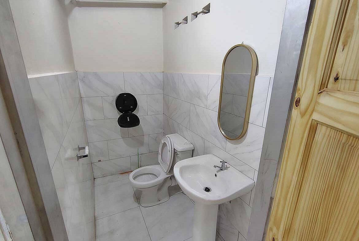 Cornerstone- Small commercial restroom with toilet and sink in Curepe.
