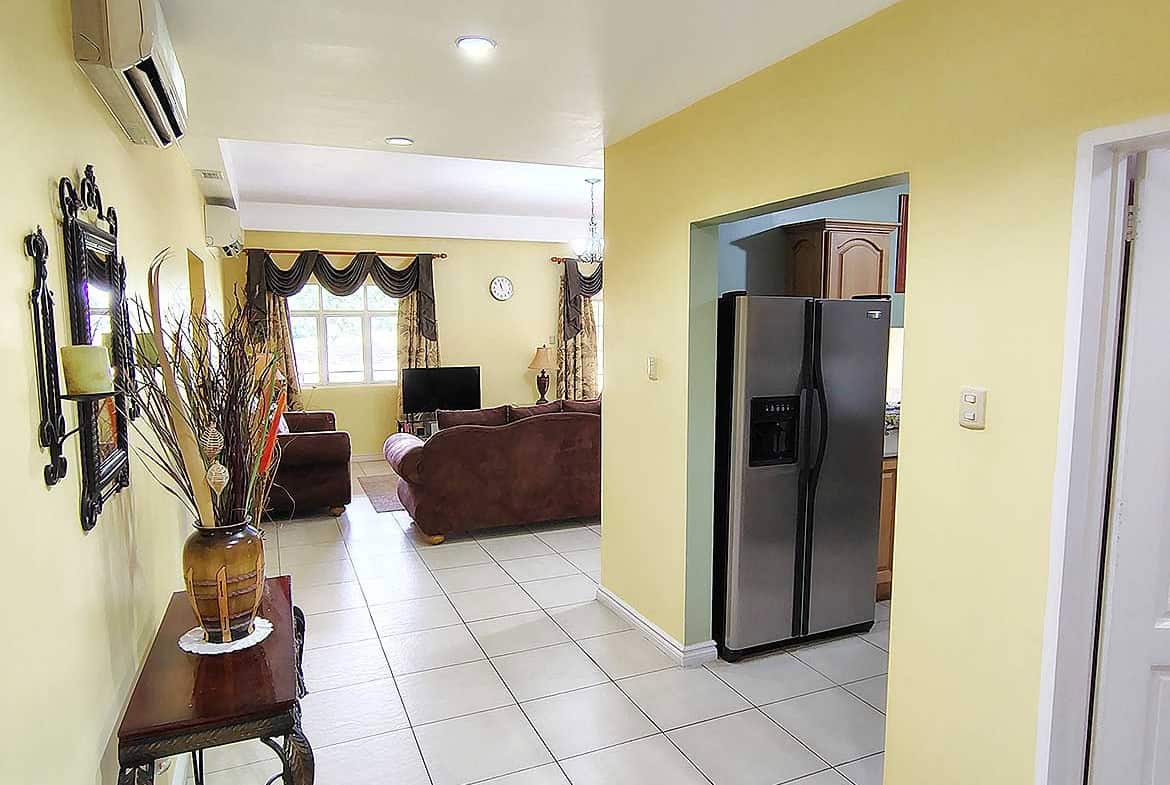 Spacious living room with modern furniture and kitchen area at EastGate on the Greens.