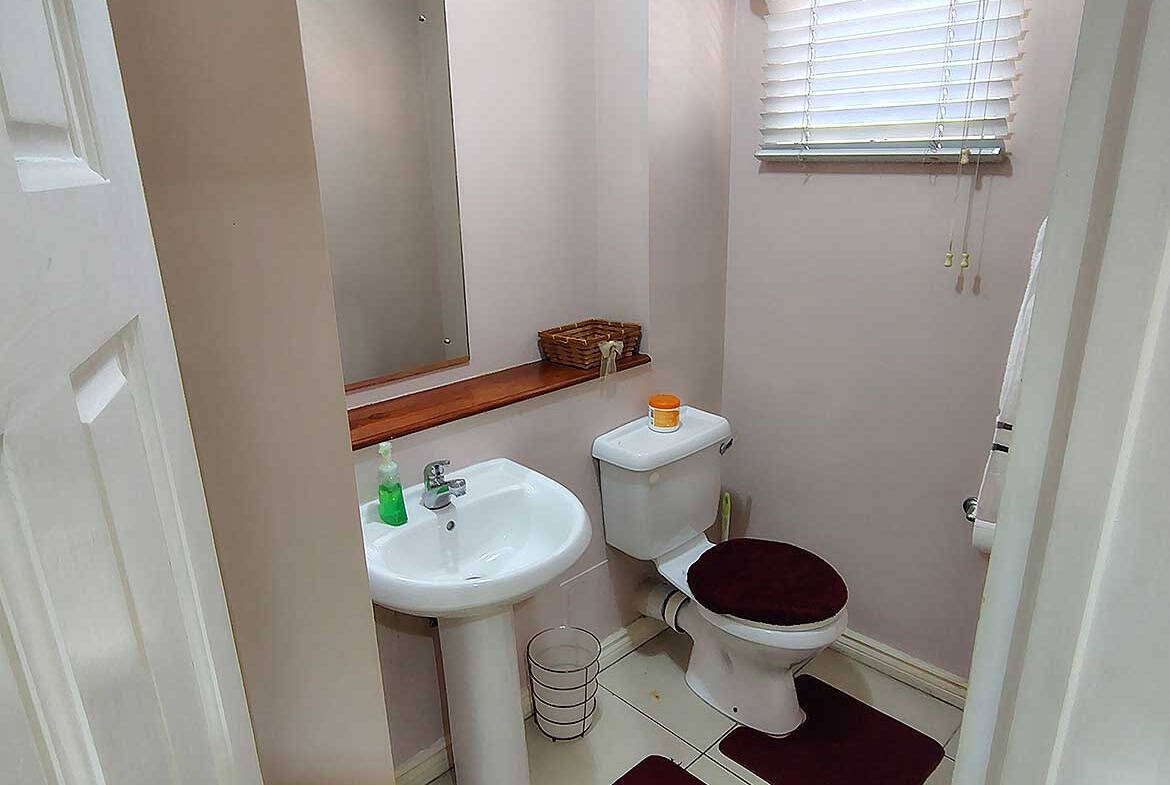 Small bathroom with sink, toilet, mirror, and window with blinds.
