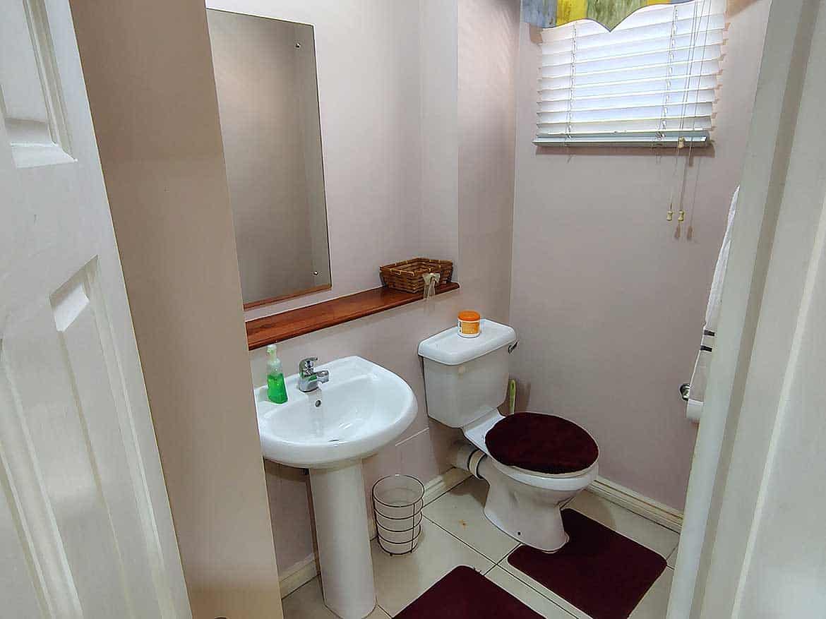 EastGate on the Greens Bathroom Small bathroom with sink, toilet, mirror, and window with blinds.