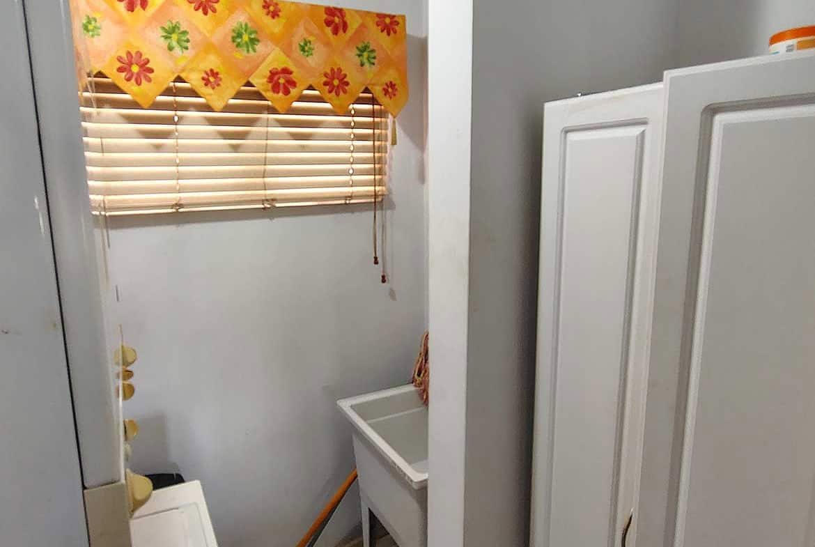Laundry room with window, colorful valance, and utility sink.