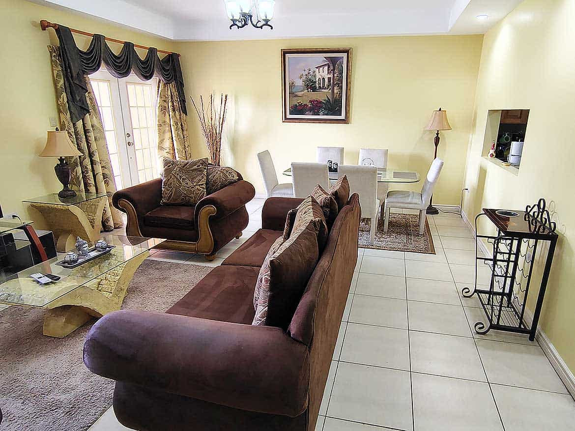 Living Room at EastGate on the Greens Spacious living room with sofas, dining area, and decorative curtains.