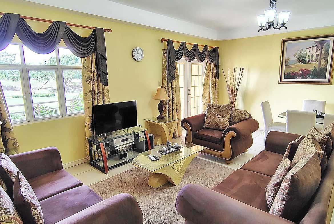 Spacious living room with yellow walls, large windows, and elegant furniture.