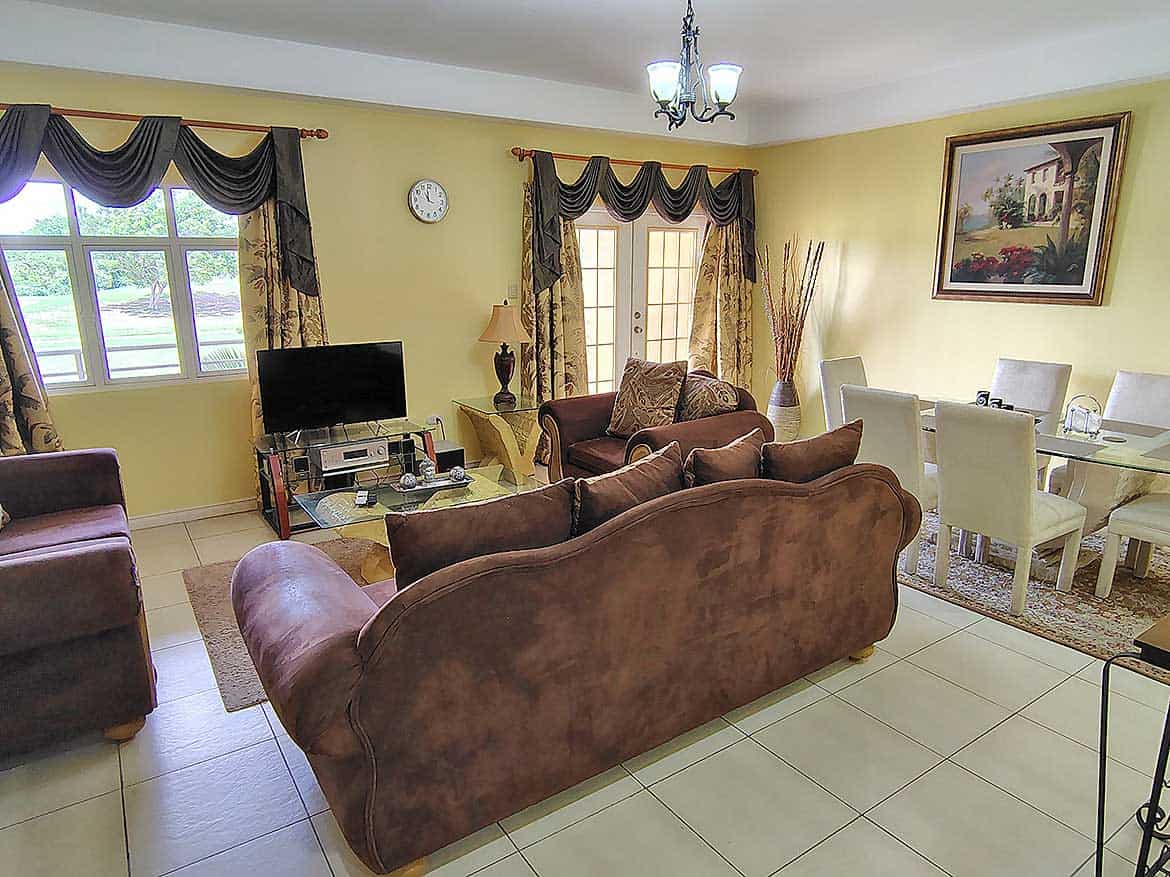 EastGate on the Greens Living Room Spacious living room with brown sofas, dining area, and large windows.