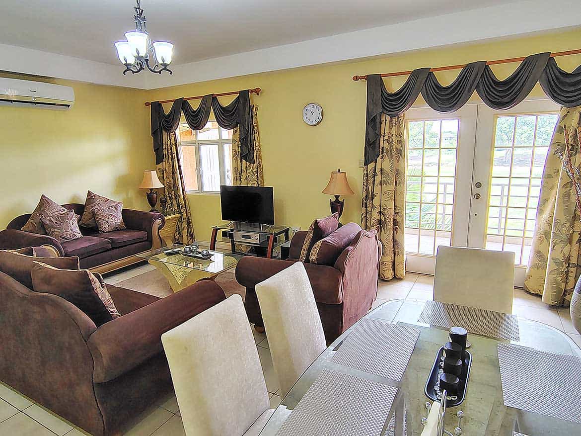 Elegant Living Room at EastGate on the Greens Spacious living room with comfortable sofas, curtains, and a TV in EastGate on the Greens.