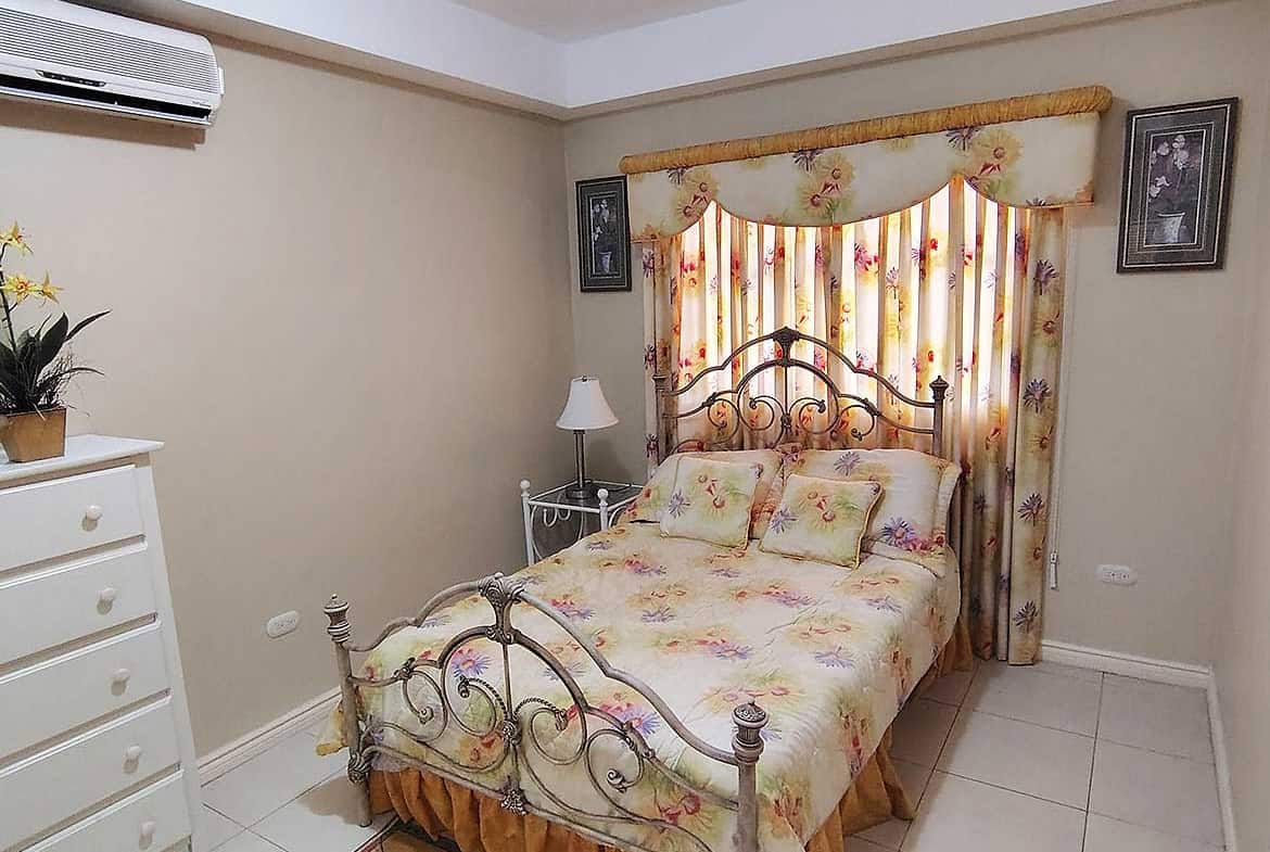 Cozy bedroom with floral curtains and vintage bed frame.
