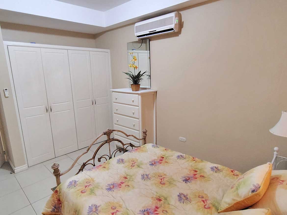 Bedroom with Air Conditioner and Wardrobe Bedroom with air conditioner, white wardrobe, and floral bedspread.