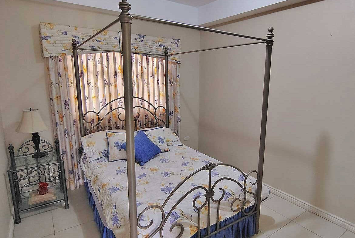 Spacious bedroom featuring a decorative four-poster bed and floral curtains.