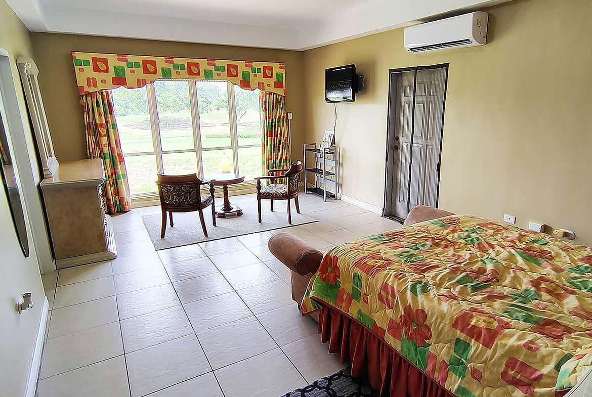 Spacious hotel room with large window and colorful curtains at EastGate on the Greens.