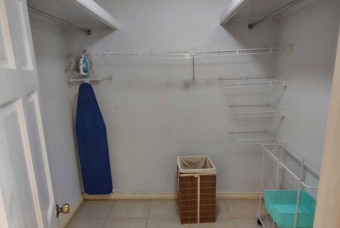 Empty closet with shelves, ironing board, and laundry basket at EastGate on the Greens.