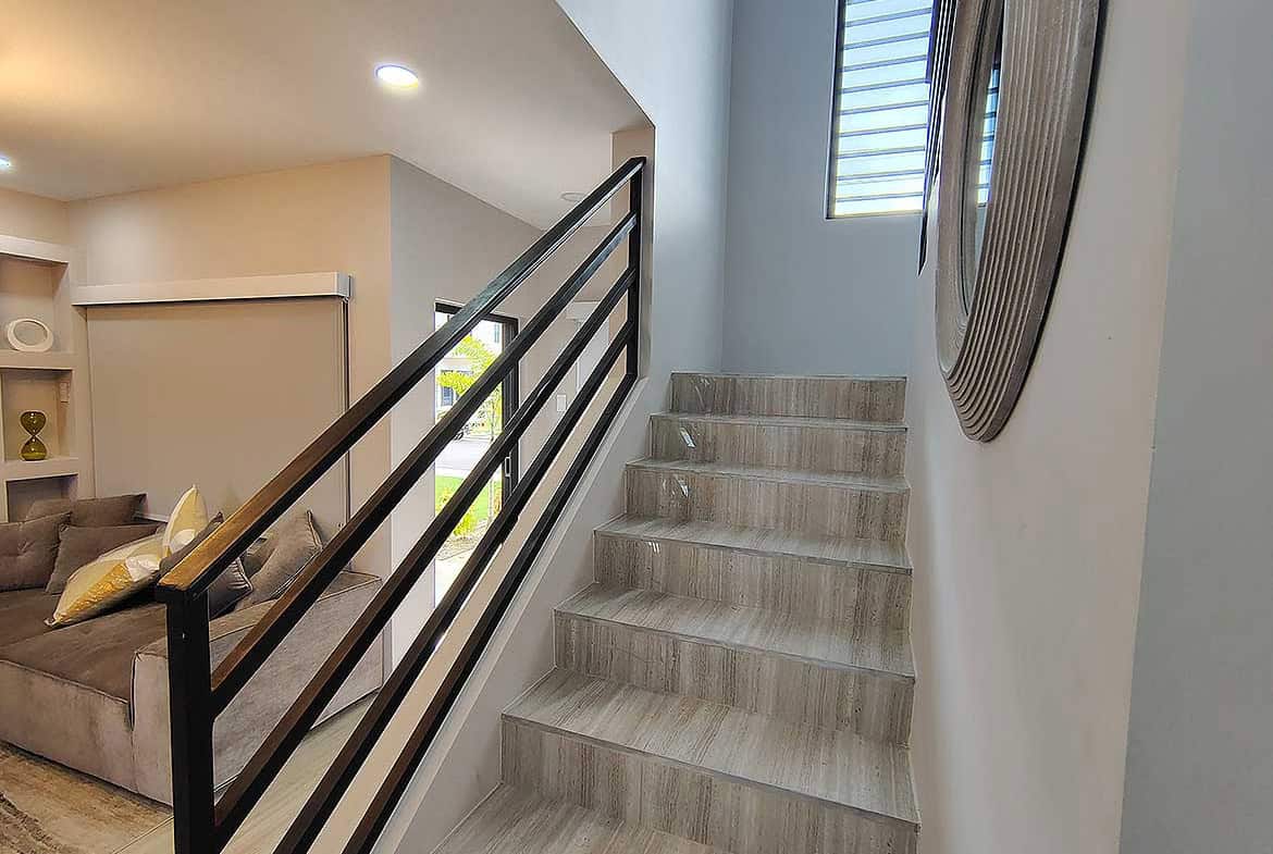 Modern interior staircase with wooden steps and black metal railing in Ella Vista Gardens.