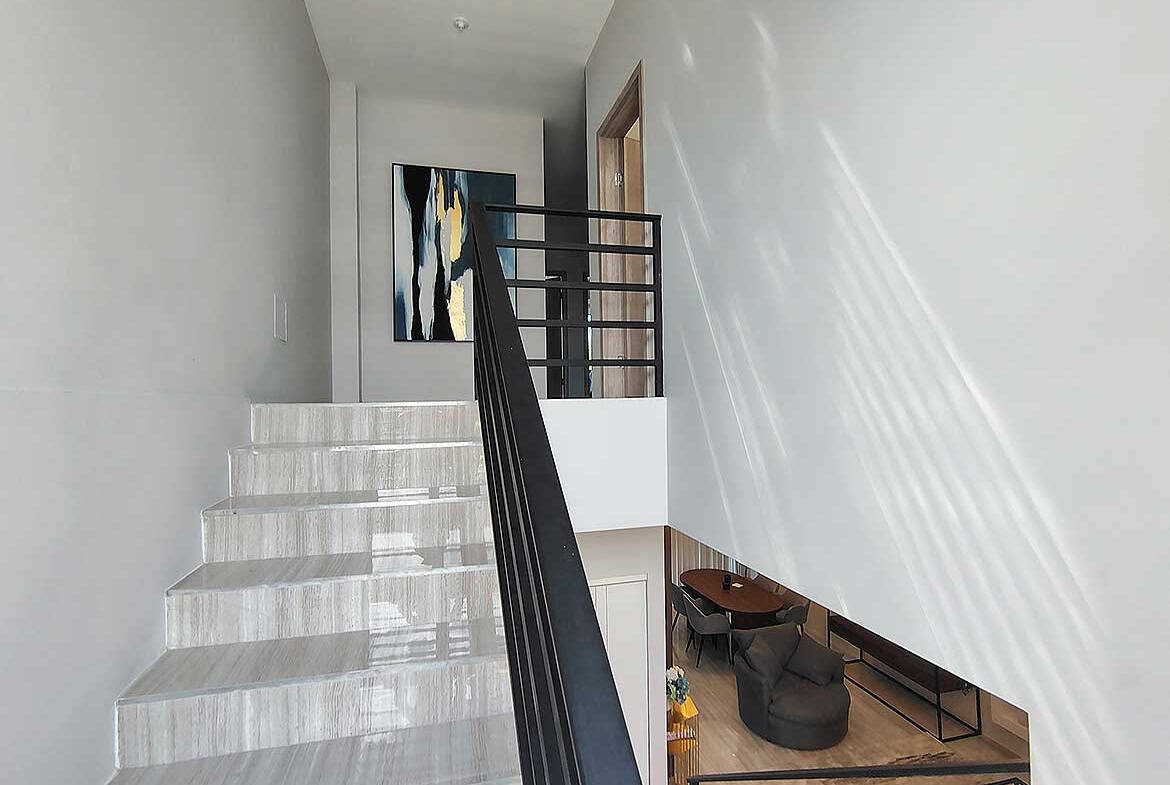 Modern interior staircase with white marble steps and black railing.