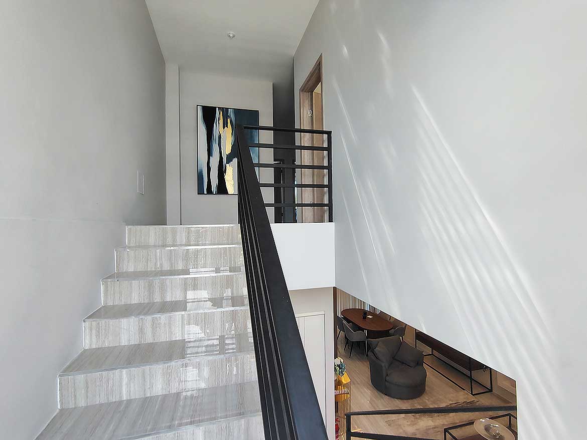 Interior Staircase at Ella Vista Gardens Modern interior staircase with white marble steps and black railing.