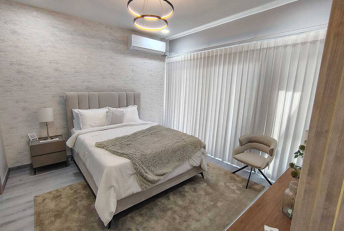 Modern bedroom with large window, cozy bed, and stylish decor at Ella Vista Gardens.