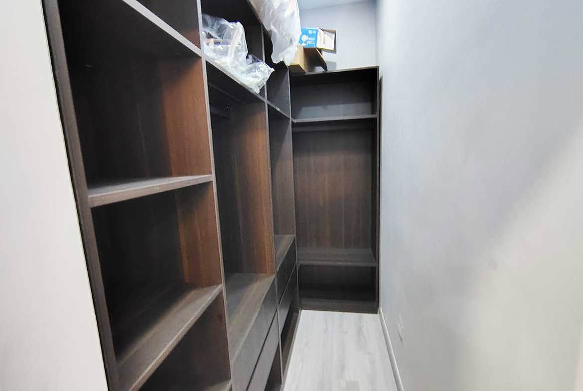 Built-in wooden shelves in a narrow storage room at Ella Vista Gardens.