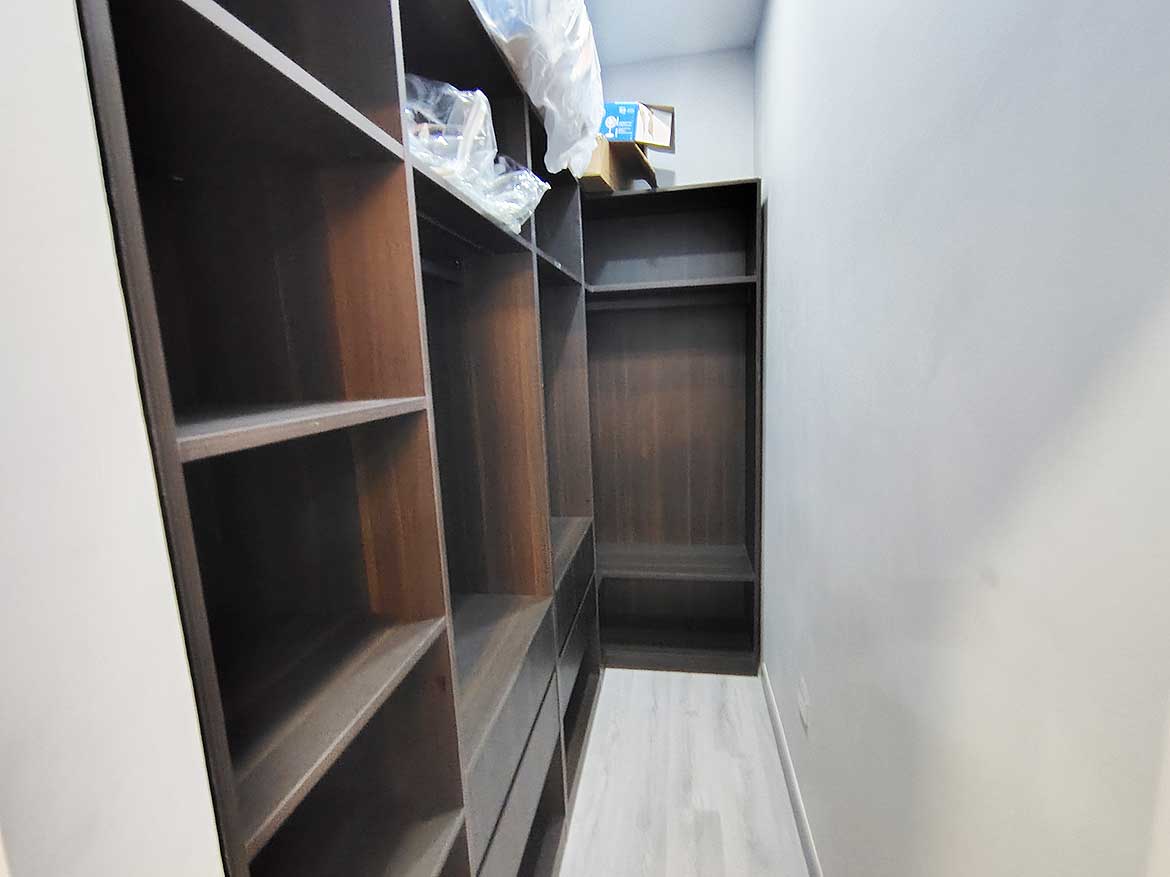 Cornerstone™ Ella Vista Gardens Storage Built-in wooden shelves in a narrow storage room at Ella Vista Gardens.