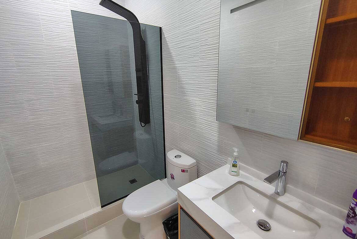 Contemporary bathroom with walk-in shower, toilet, and vanity at Ella Vista Gardens.