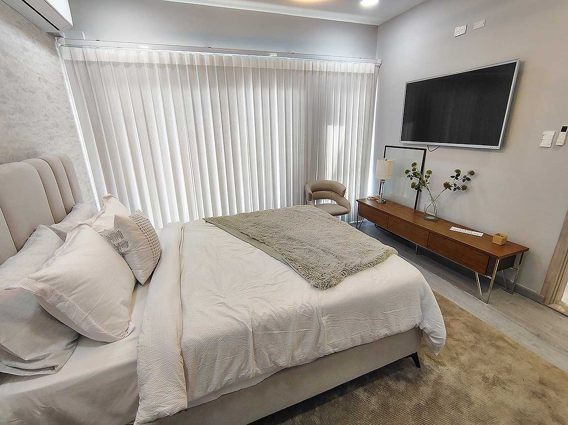 Ella Vista Gardens Bedroom Interior Modern bedroom with large window, TV, and stylish decor at Ella Vista Gardens.