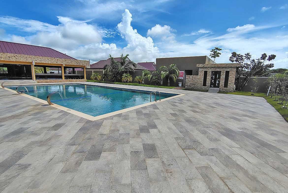 Outdoor swimming pool at Ella Vista Gardens with surrounding patio and lush greenery.