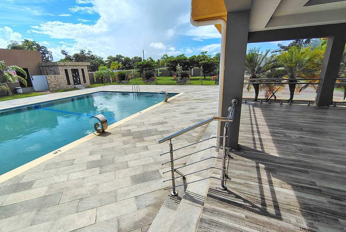 Swimming pool at Ella Vista Gardens with surrounding lounge area and lush greenery.