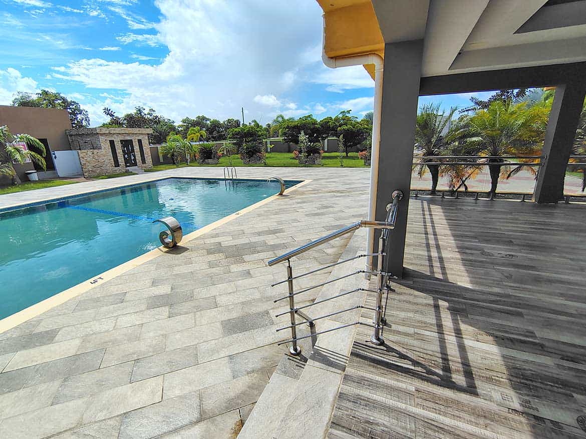 Cornerstone™ Ella Vista Gardens Pool Area Swimming pool at Ella Vista Gardens with surrounding lounge area and lush greenery.