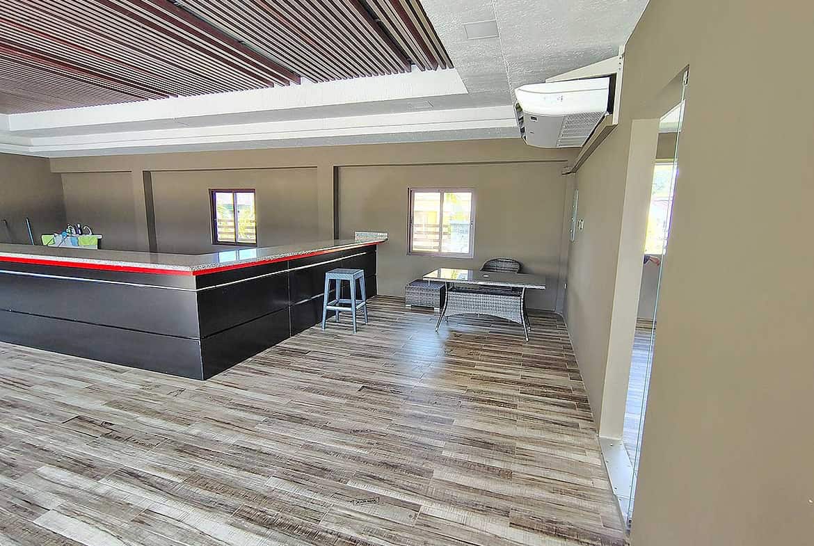 Spacious lounge with bar, seating, and large windows at Ella Vista Gardens.