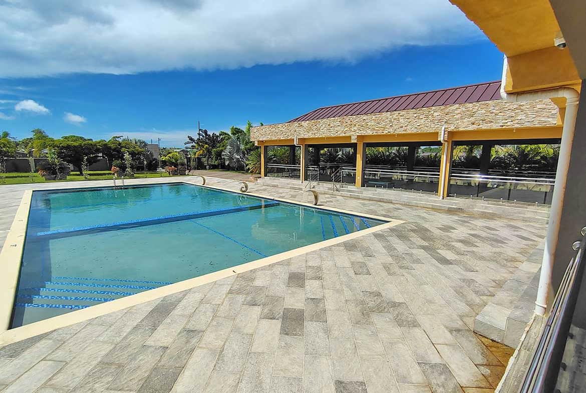 Swimming pool at Ella Vista Gardens with surrounding patio and covered seating area.