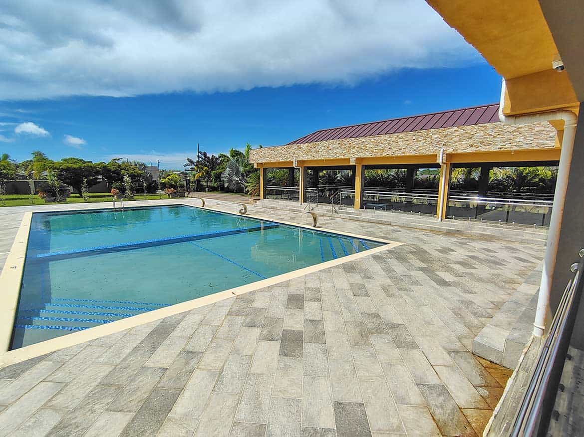 Ella Vista Gardens Pool Area Swimming pool at Ella Vista Gardens with surrounding patio and covered seating area.