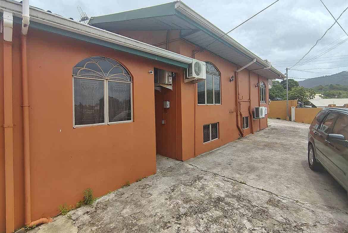 Cornerstone- Residential building on Cleaver Road, Arima with parking area and air conditioning units.
