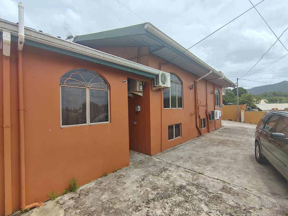 Cornerstone™ Residential Property in Arima Cornerstone- Residential building on Cleaver Road, Arima with parking area and air conditioning units.