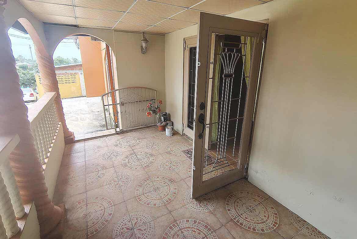 Cornerstone- Front porch of Cornerstone™ property in Arima with open door and tiled floor.