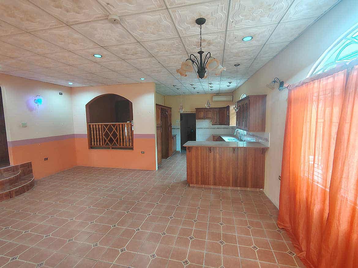 Spacious Kitchen and Living Area Cornerstone- Bright kitchen and living space with orange curtains and tiled flooring.