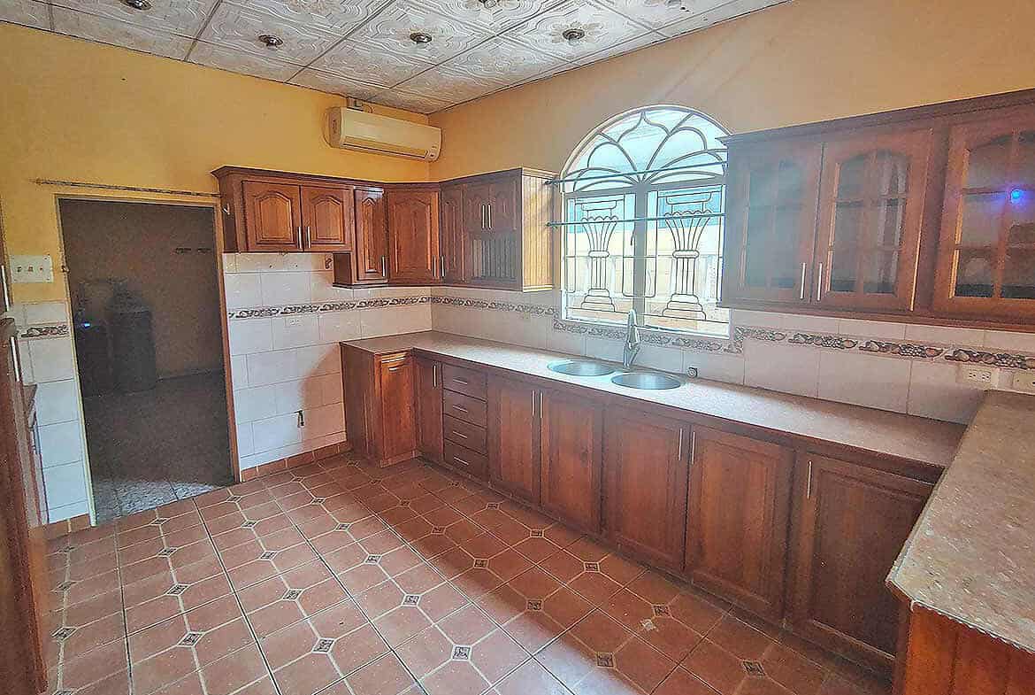 Cornerstone- Kitchen with wooden cabinets, tiled floor, and arched window.
