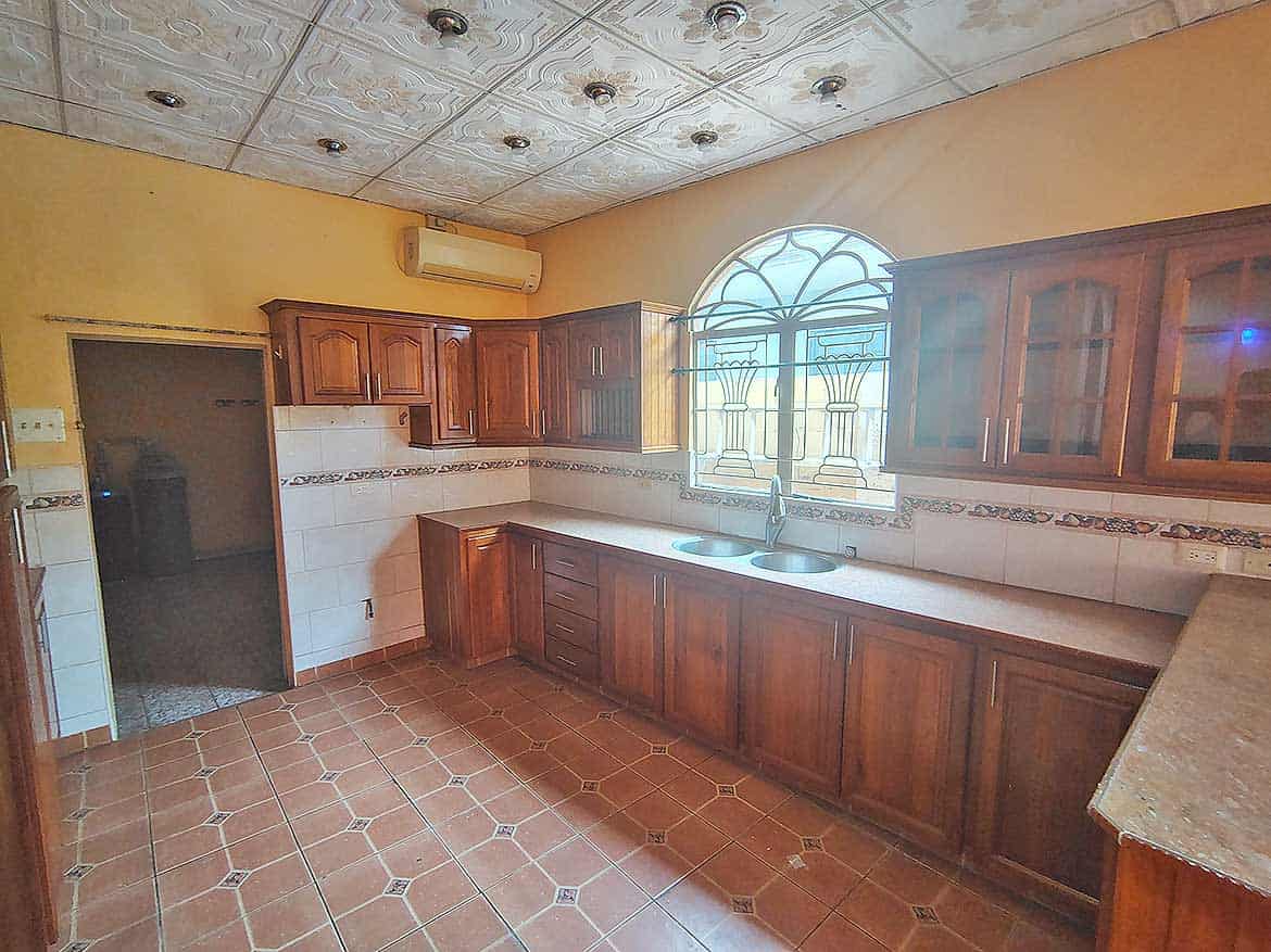 Spacious Kitchen with Wooden Cabinets Cornerstone- Kitchen with wooden cabinets, tiled floor, and arched window.