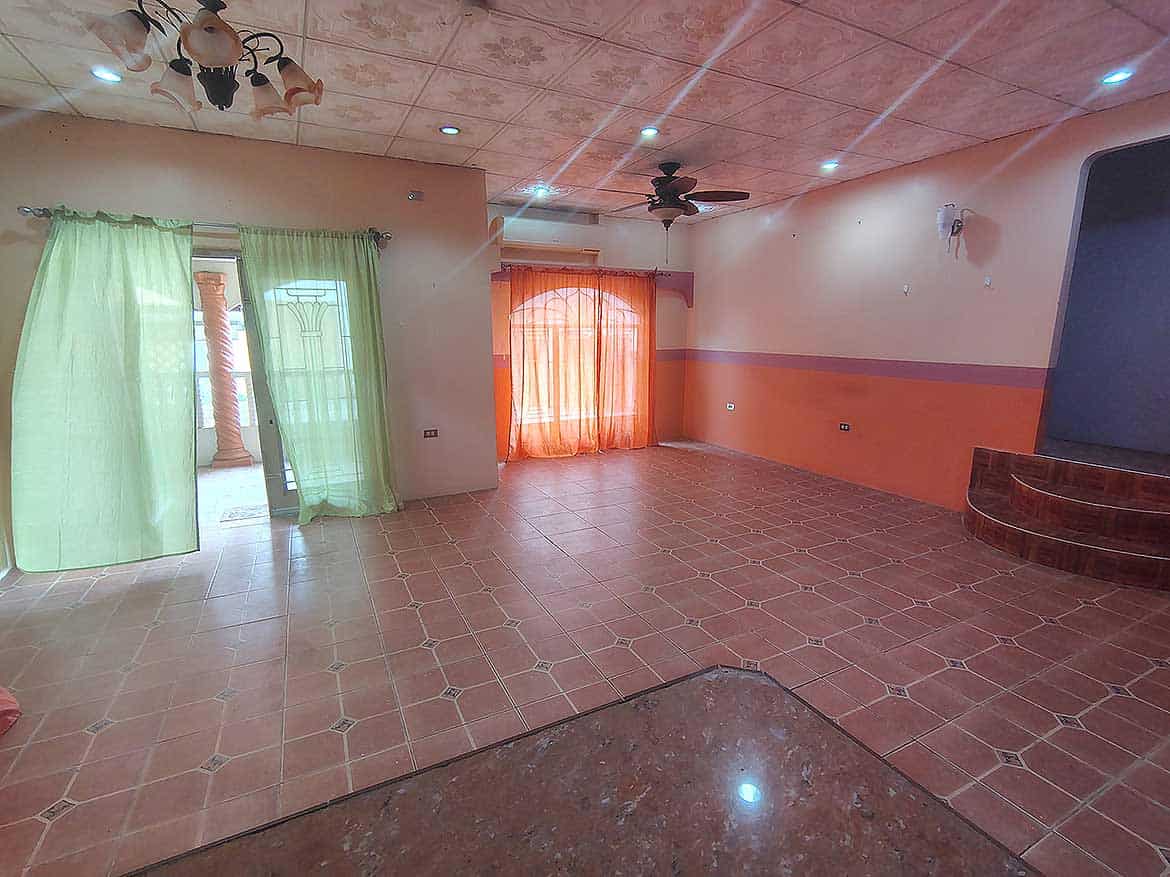 Spacious Living Room in Arima Cornerstone- Bright living room with green and orange curtains, tiled floor, and ceiling fan.