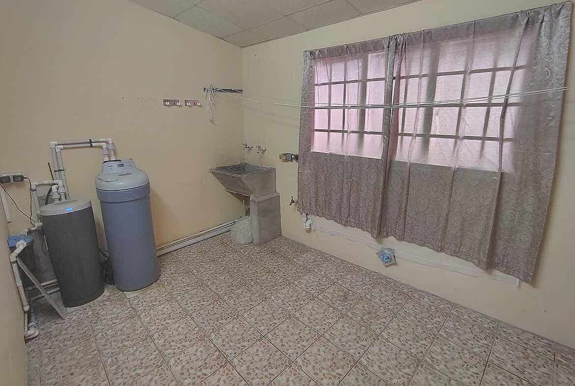 Cornerstone- Empty room with water filter system and window with curtains.
