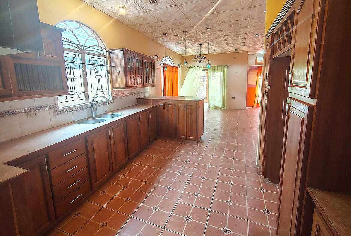 Cornerstone- Bright kitchen with wooden cabinets and tiled floor in Arima.