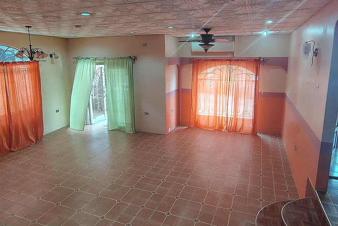 Cornerstone- Bright living room with colorful curtains and tiled floor in Arima property.