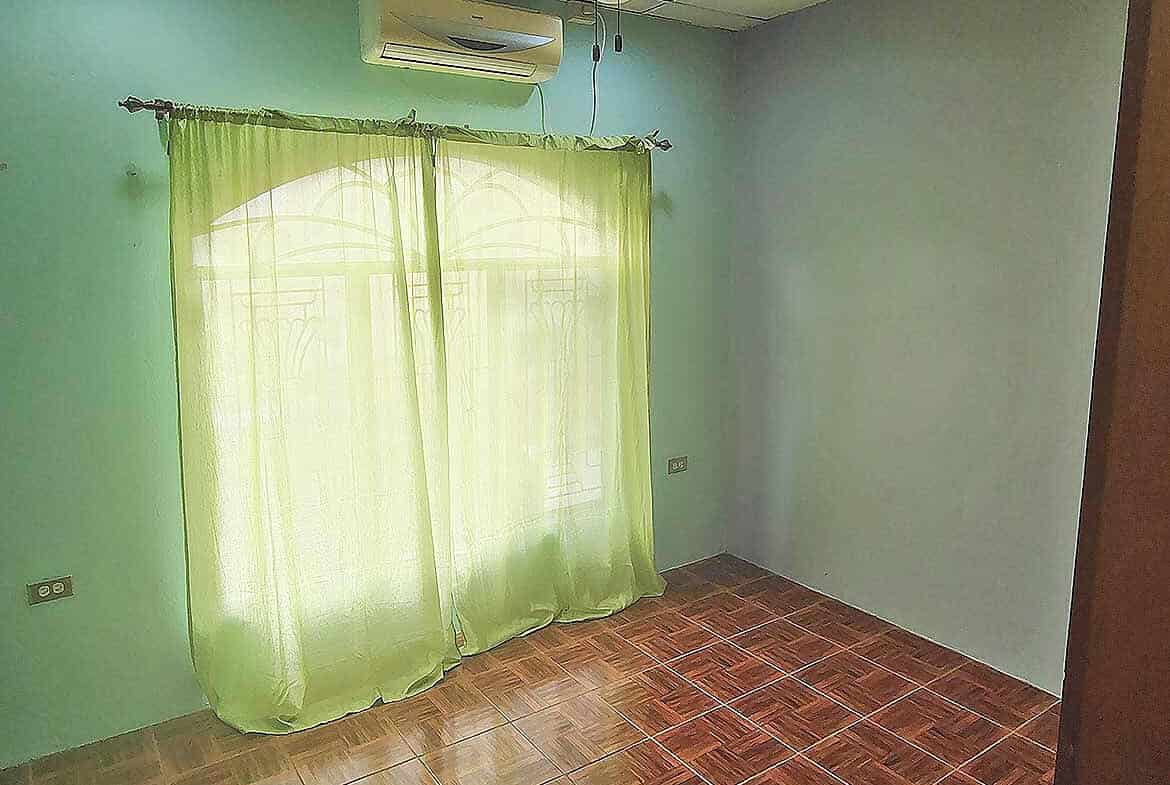 Cornerstone- Empty room with green curtains, ceiling fan, and air conditioner in Arima.