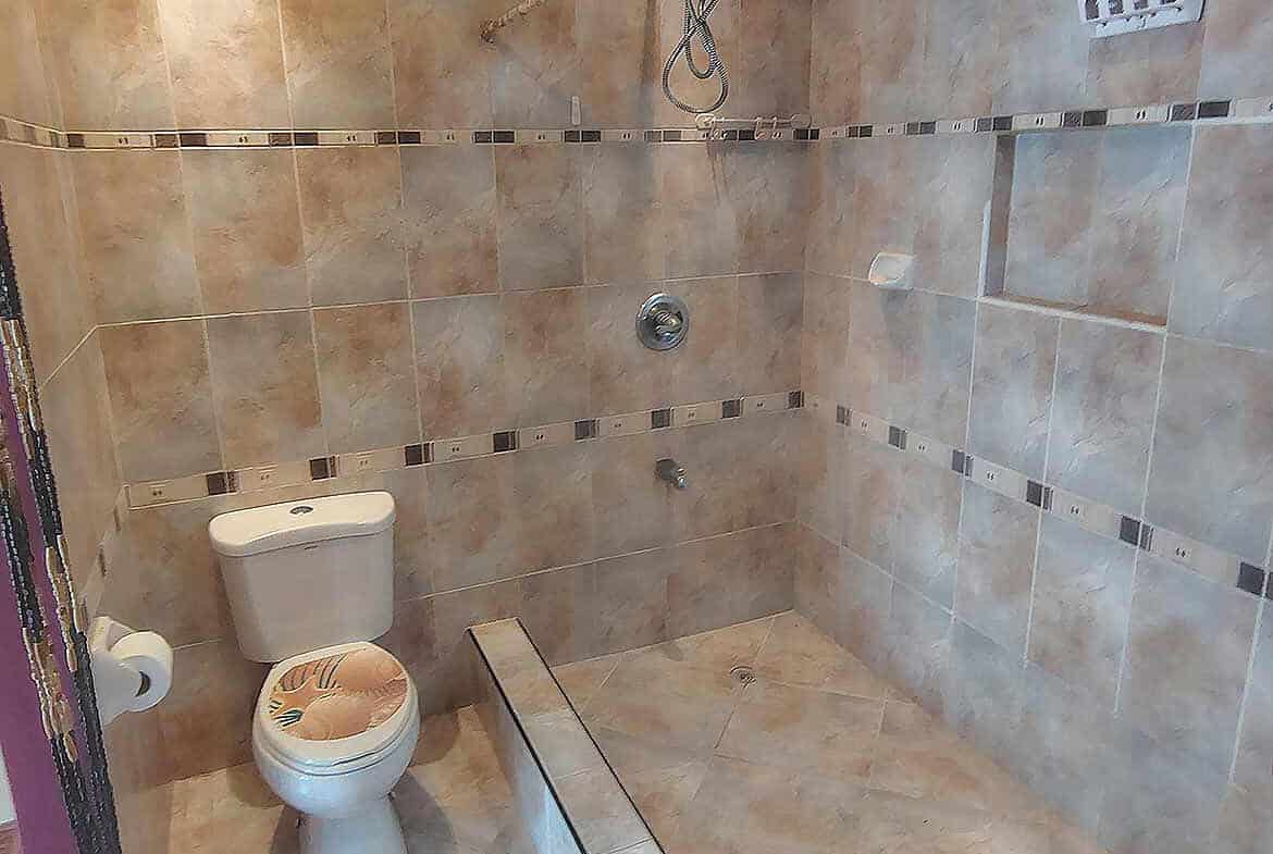 Cornerstone- Bathroom shower with tiled walls and toilet at Cornerstone™.