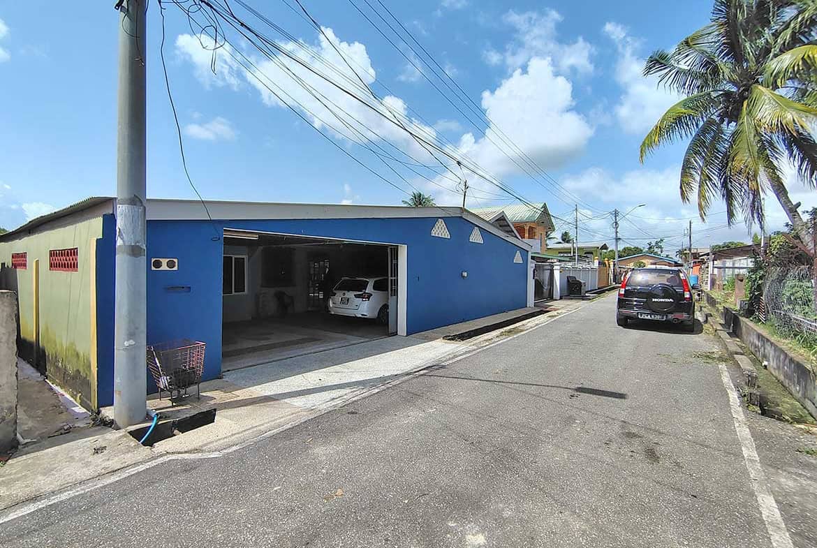 Blue residential building with garage and parked cars on a sunny day.