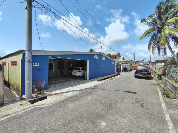 Blue residential building with garage and parked cars on a sunny day.