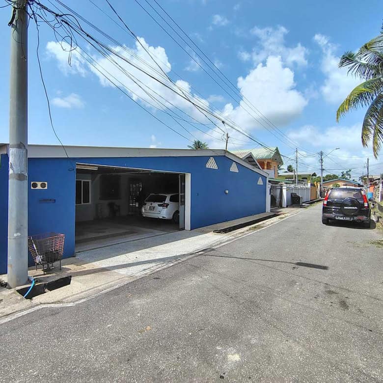 Blue residential building with garage and parked cars on a sunny day.